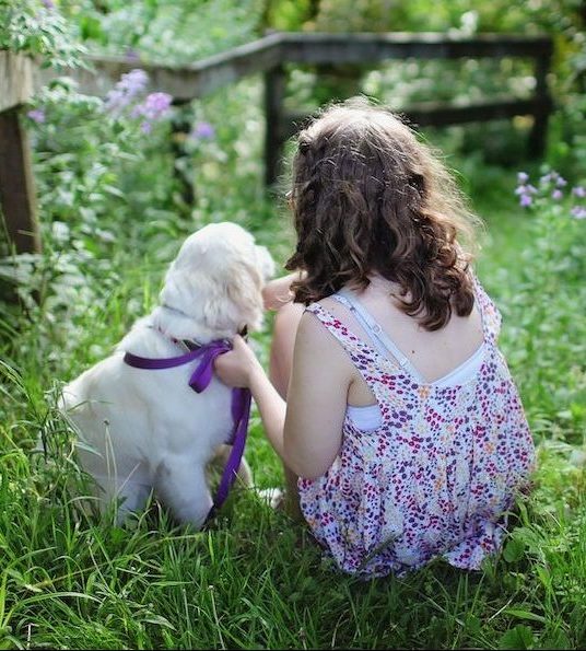 A little girl sitting with her puppy.